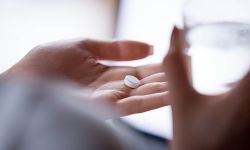 Close up woman holding pill in hand with water