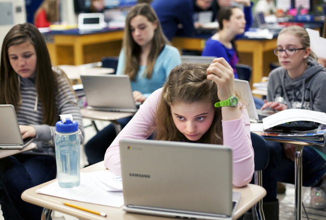 8th grader Emma Clark, 14, ponders a problem during a science class at the DeWitt Junior High School in DeWitt, Michigan. Students at DeWitt commonly use technology in classroom, sometimes working on their personal devices, other times using school provided laptops. Schools in smaller communities like DeWitt struggle with funding and can't always afford the technology deemed essential in today's world. (Bridge photo by Marcin Szczepanski)