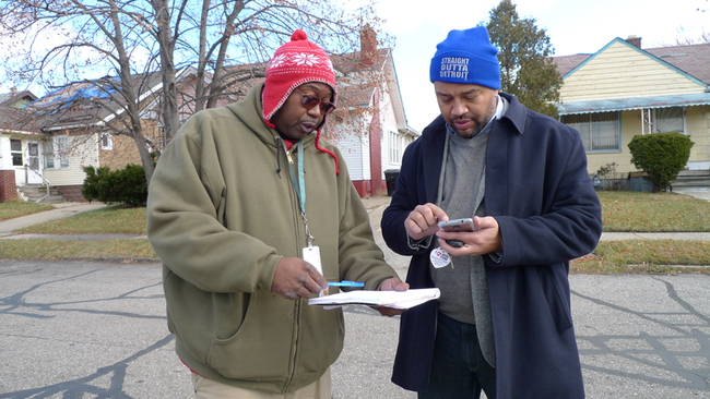 Anthony Sykes, left, and Marshall Bullock confer on an upcoming blight-boarding project in Detroit’s 7th Council District, which Bullock is overseeing. Sykes will provide volunteer help through Lakeshore-Rickman, the contracting firm he works for. (Bridge photo by Nancy Derringer)