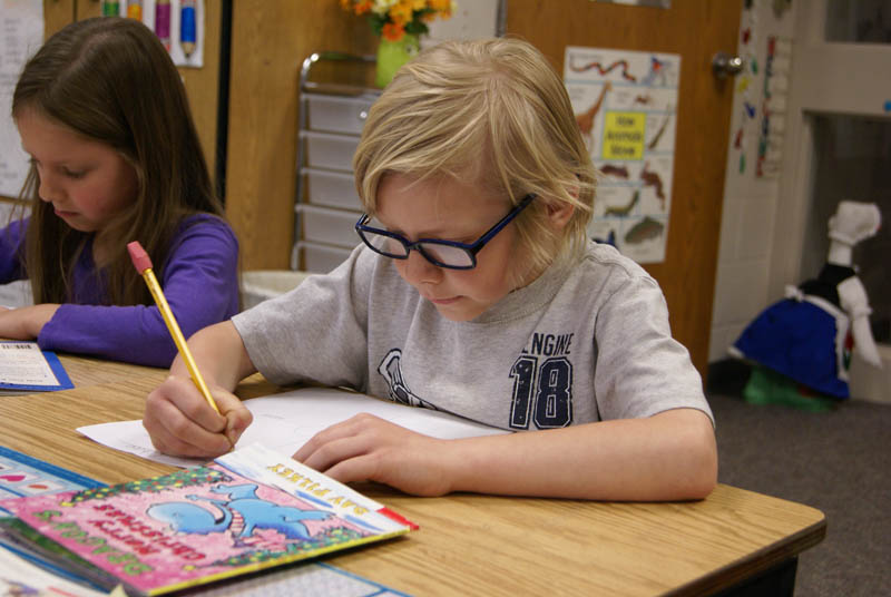 Chase Barrett, a first grader at Waukazoo Elementary, reads a "Just Right Book" and fills out a story map, answering questions about it to test his reading ability. (Bridge photo by Pat Shellenbarger) 