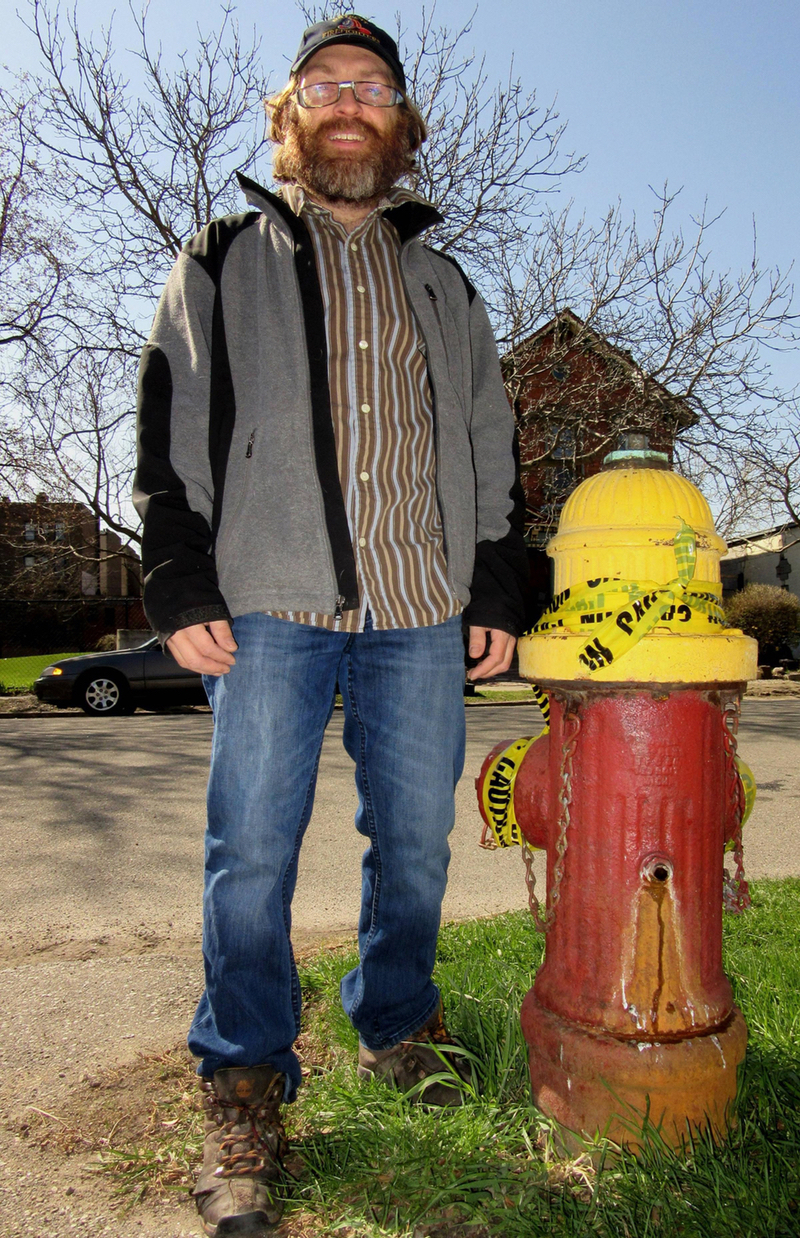 Steve Neavling, of Motor City Muckraker, stands next to a broken fire hydrant in front of where he lives. (photo by Lester Graham)