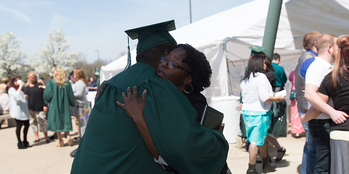Ramone Williams hugs Joi Rencher, who heads an EMU program that tries with limited funds to help the school’s homeless students. The program recently got a financial boost after Williams’s story gained attention. (Bridge photo by Brian Widdis)