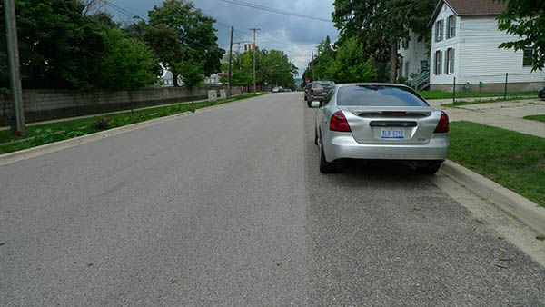 The slightly darker strip of pavement in the parking lane indicates where the porous surface begins. Because porous concrete is weaker than the conventional kind, it’s reserved for parking areas, which get less wear and tear than driving lanes. (Bridge photo by Nancy Derringer) 