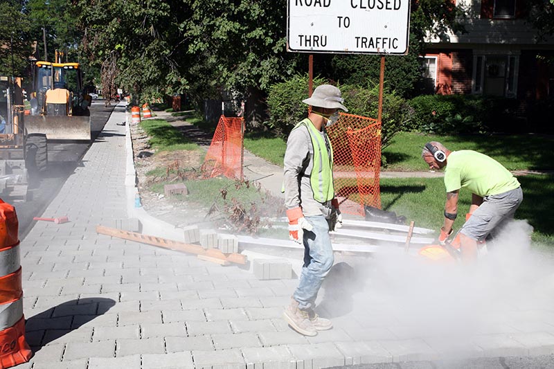 Workers at Tetra Tech, a contractor working for the City of Detroit, install pervious pavers on Keeler Street in the Rosedale Park neighborhood. The pavers have small openings allowing rainwater to pass through and soak into the ground rather than sending it into storm drains. (Bridge photo by Kurt Kuban) 