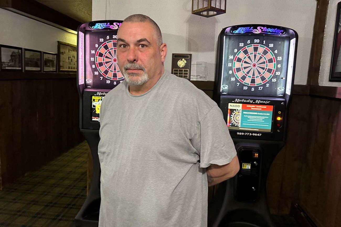 Chris Gleeson standing in a room with darts in the background