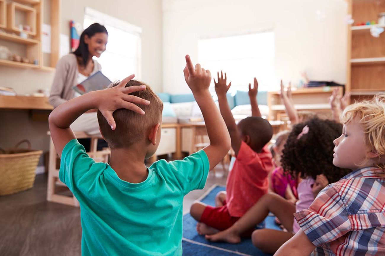 students in a classroom raising hands