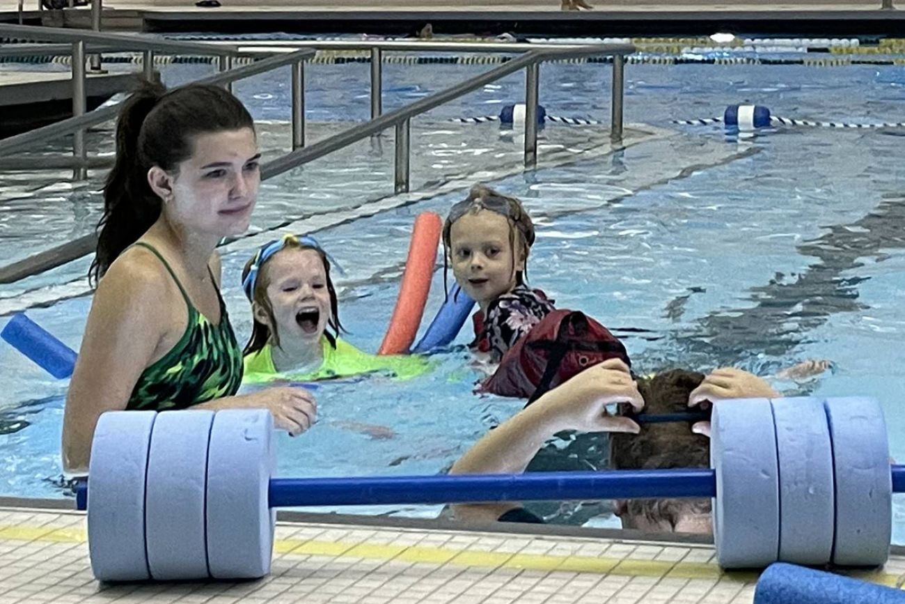 an adult and children in a pool