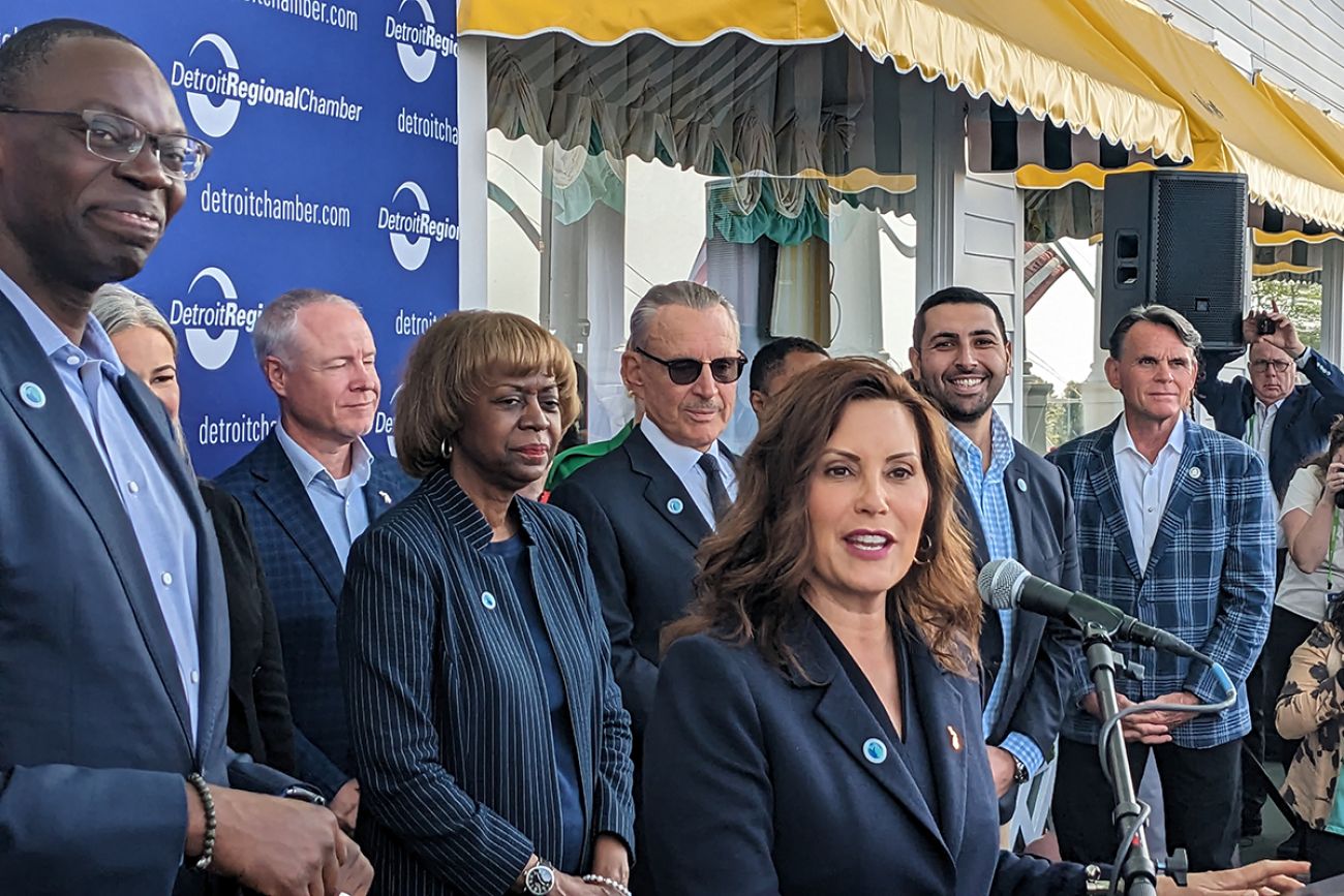 Gov. Gretchen Whitmer at the microphone surrounded by people