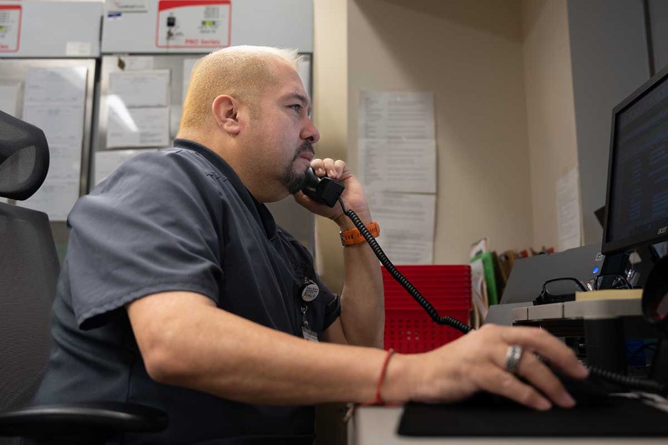 Mike Salinas talking on the phone, sitting in front of the computer