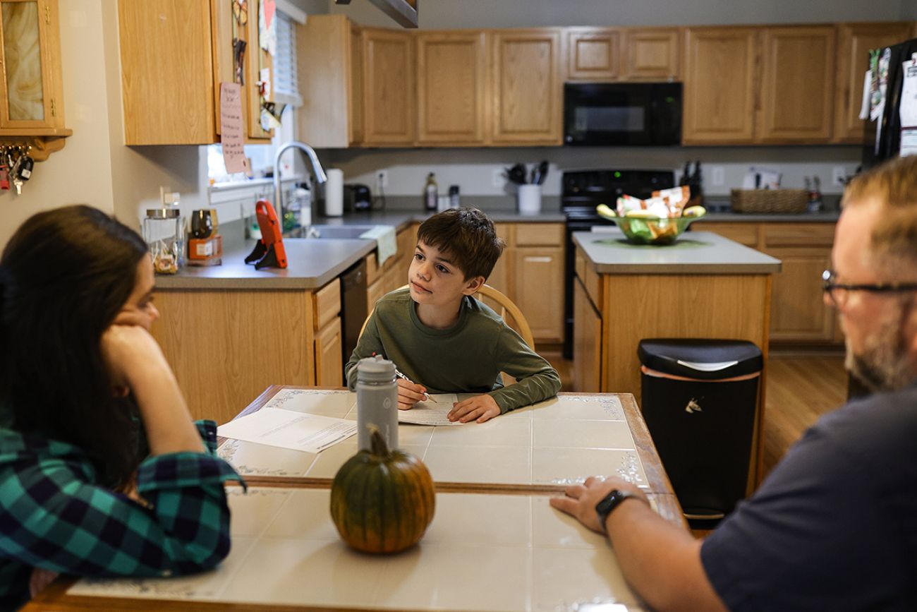 child on dining room table while parents looking at her