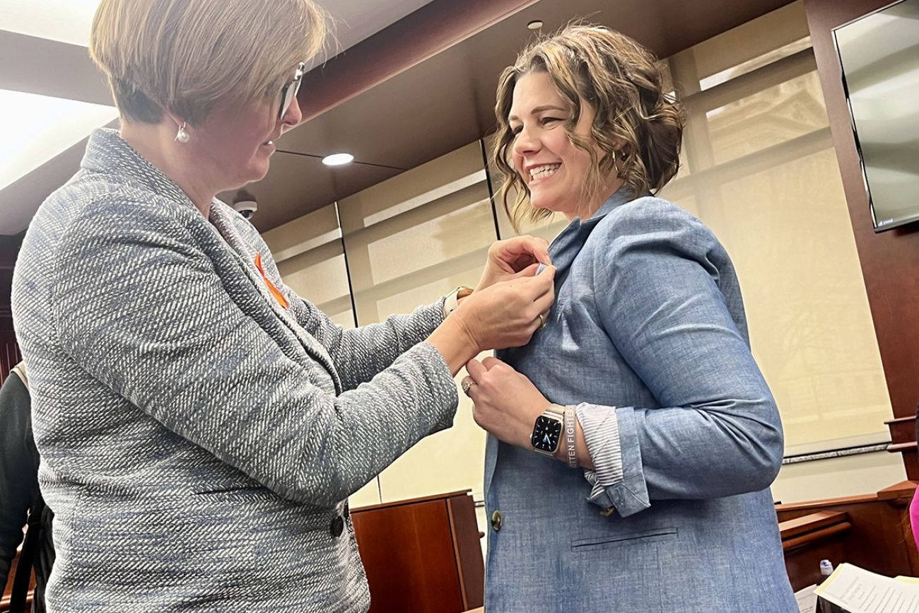 woman pinning a ribbon on another woman