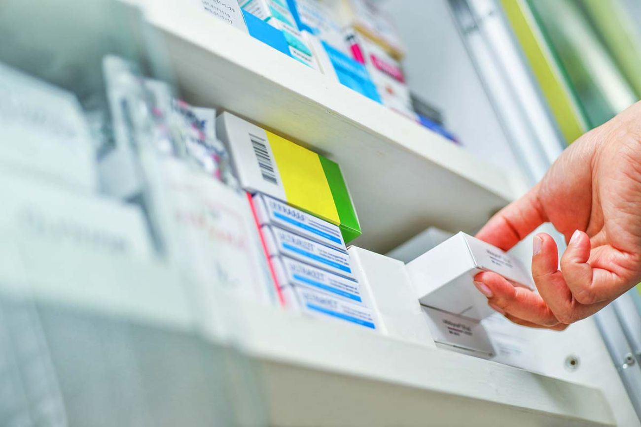 Closeup pharmacist hand holding medicine box in pharmacy drugstore.