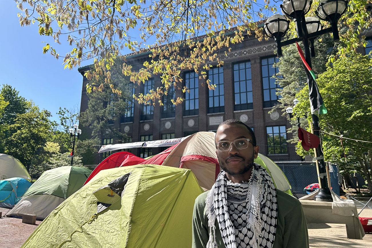 Josiah Walker poses for a photo with tents behind him