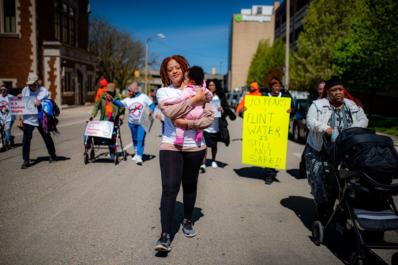 Woman holding her baby while walking in the street