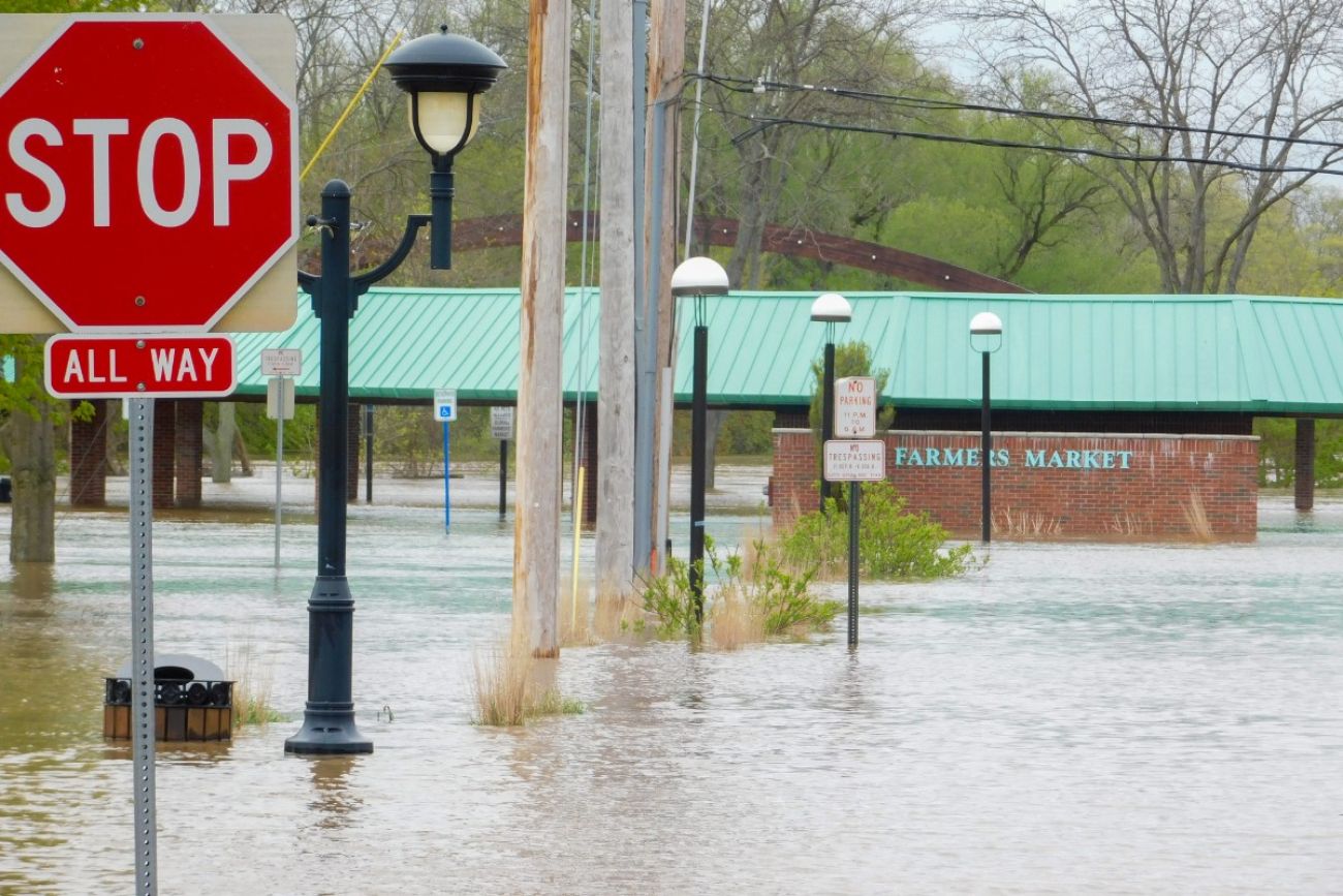 A flooded street. in the background, you can see a sign for a farmer's market