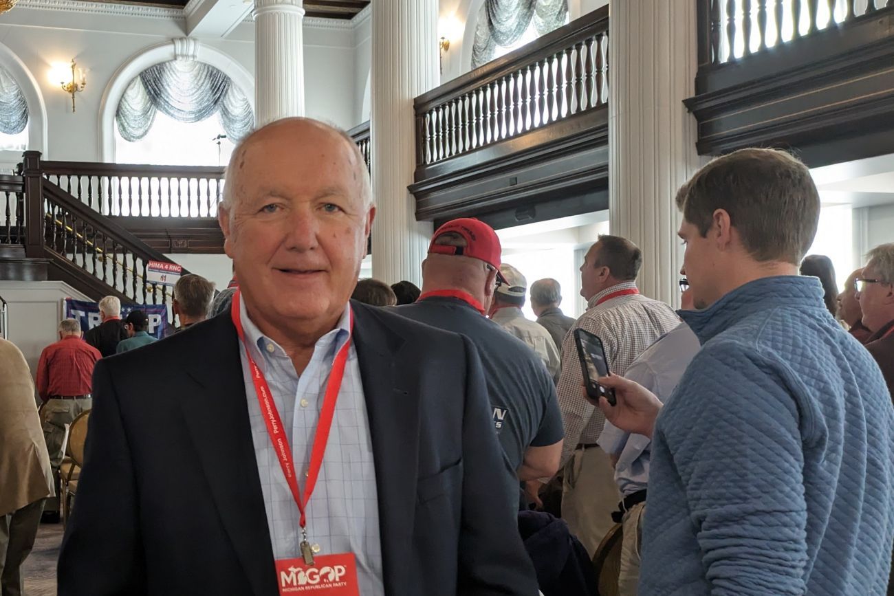 Michigan GOP Chair Pete Hoekstra posing for a picture. There a room full of people in the background