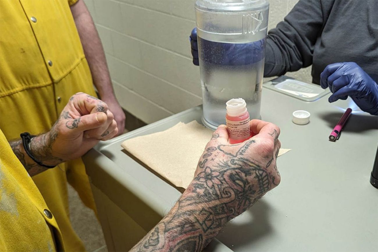 Someone getting methadone. The photo is close up of a man's hands