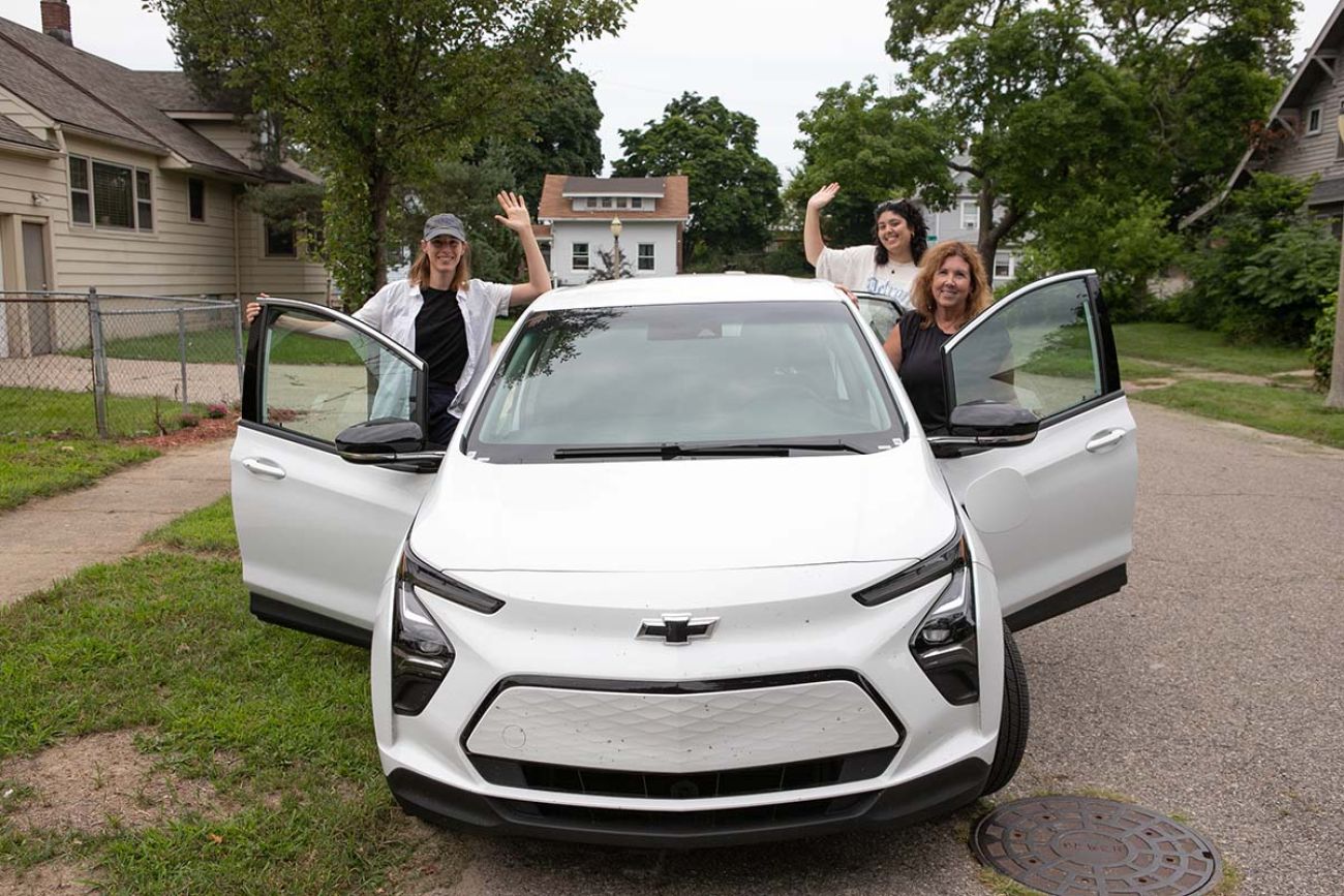 Reporters posing around a white EV