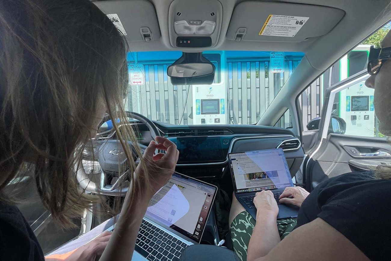 Kelly House and Paula Gardner working on their laptops in an EV car