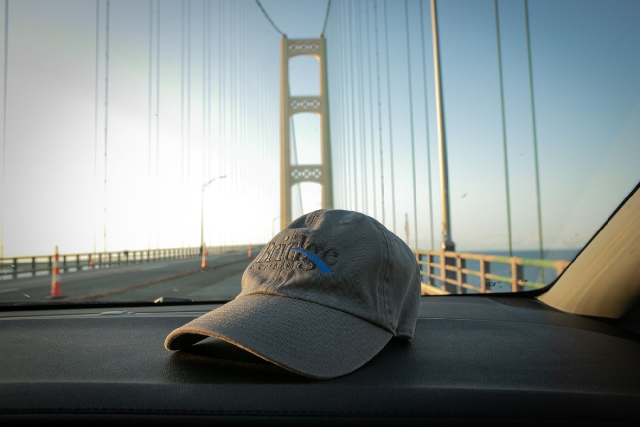 A Bridge Michigan hat on the car dashboard, the Mackinaw Bridge in the background