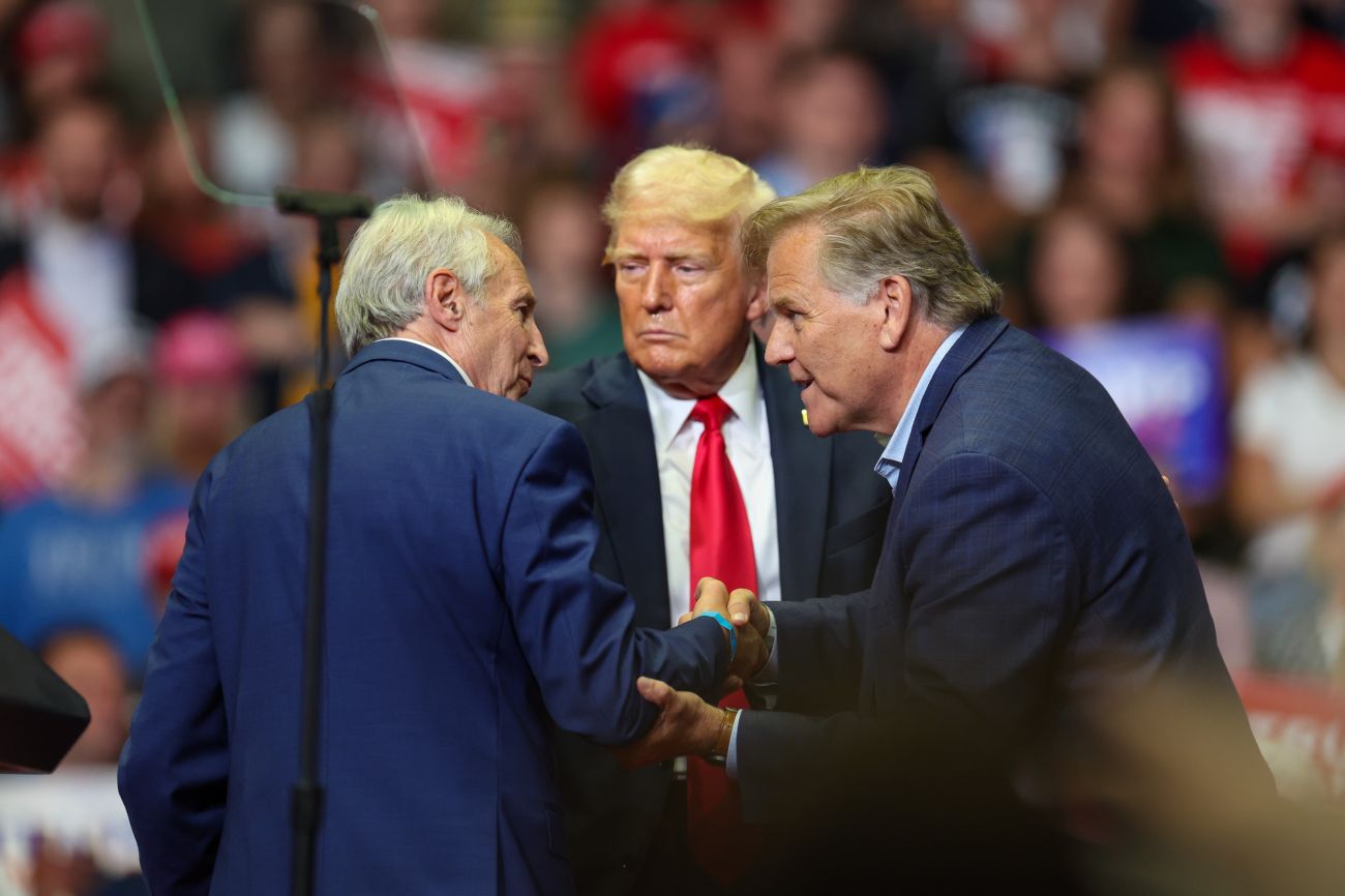 Sandy Pensler shakes hands with Mike Rogers as Donald Trump looks on
