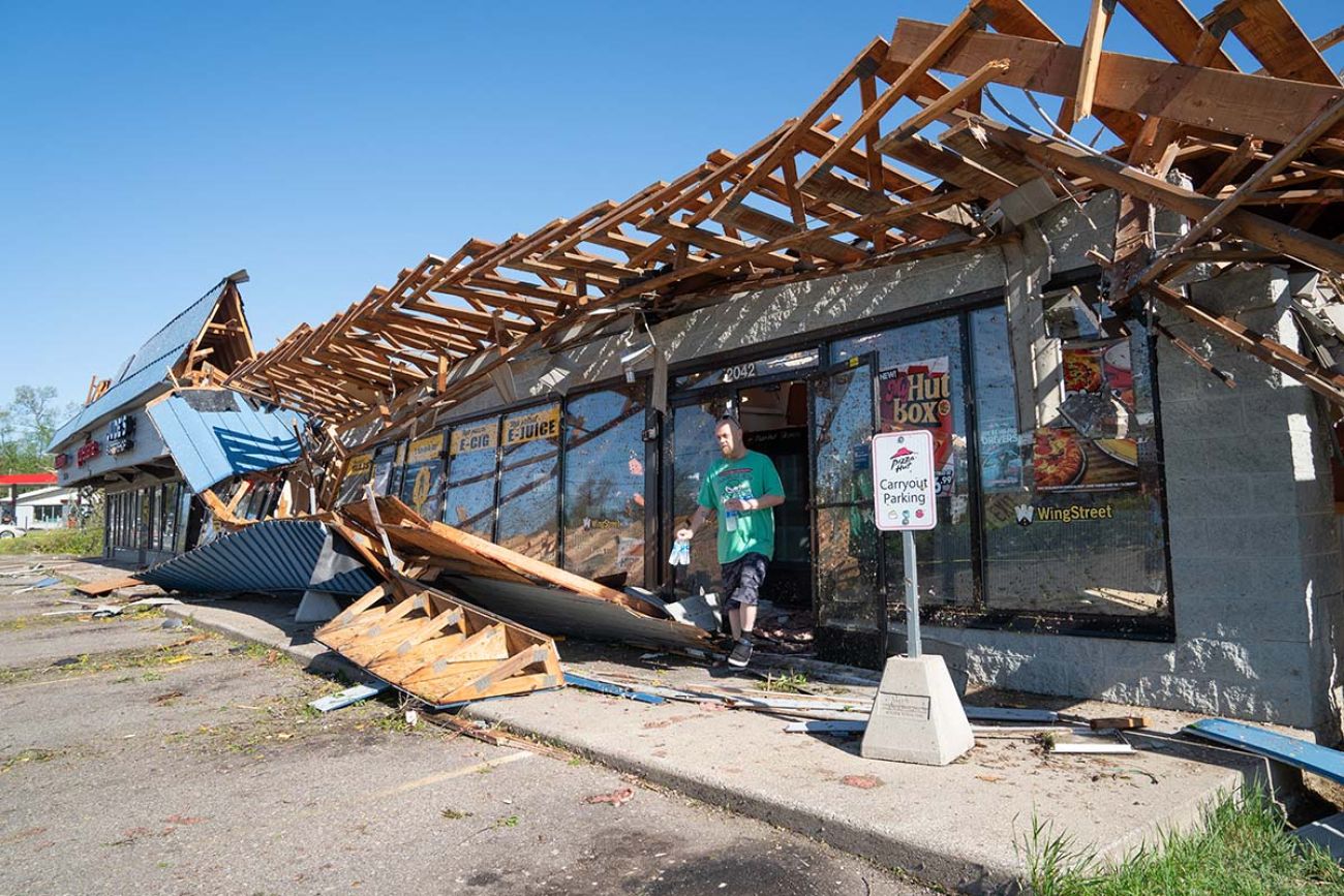 Severely damaged this Pizza Hut from a tornado in Portage, Michigan. A man is walking out of the store