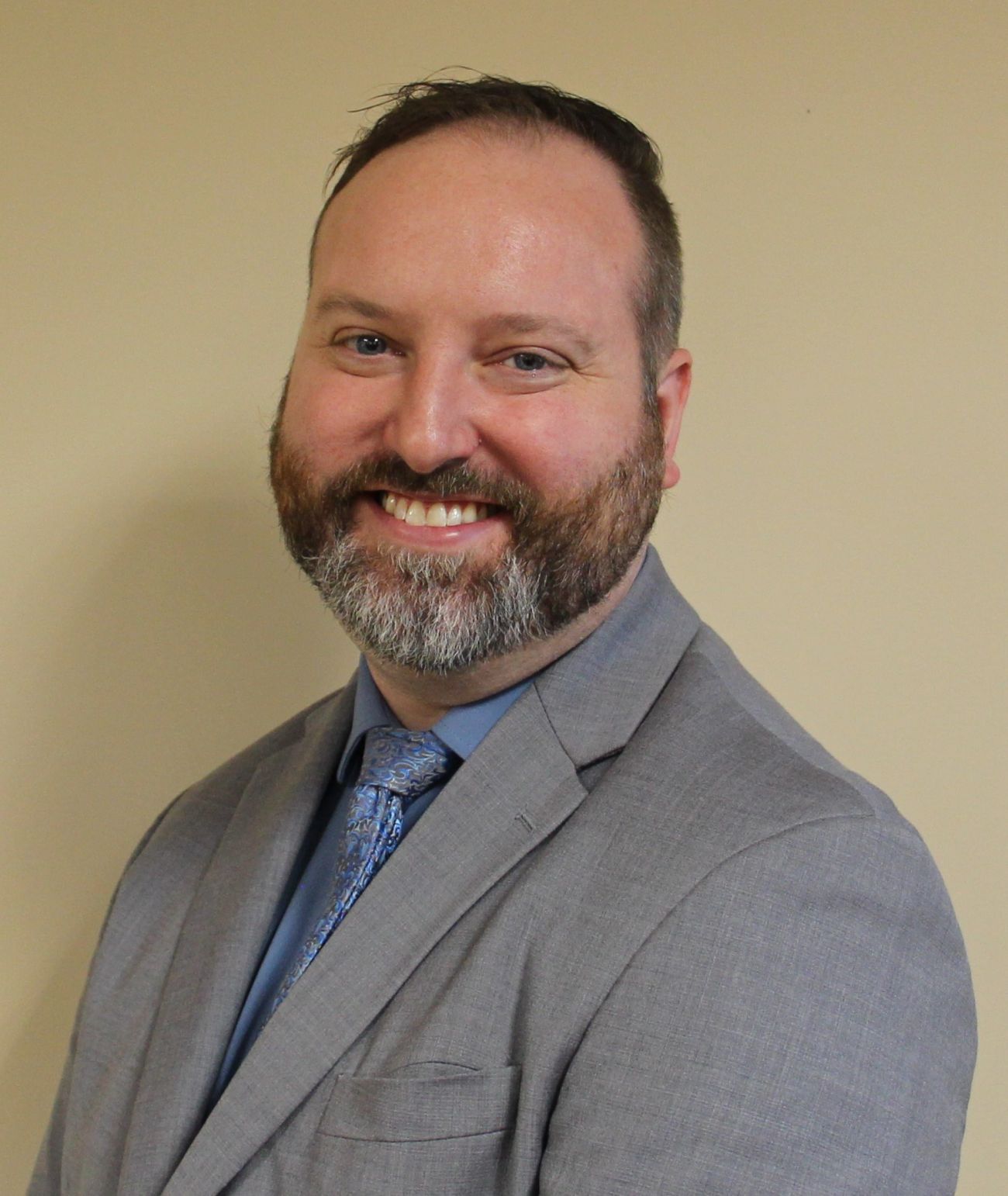  Eric Roath headshot. He is wearing a grey suit