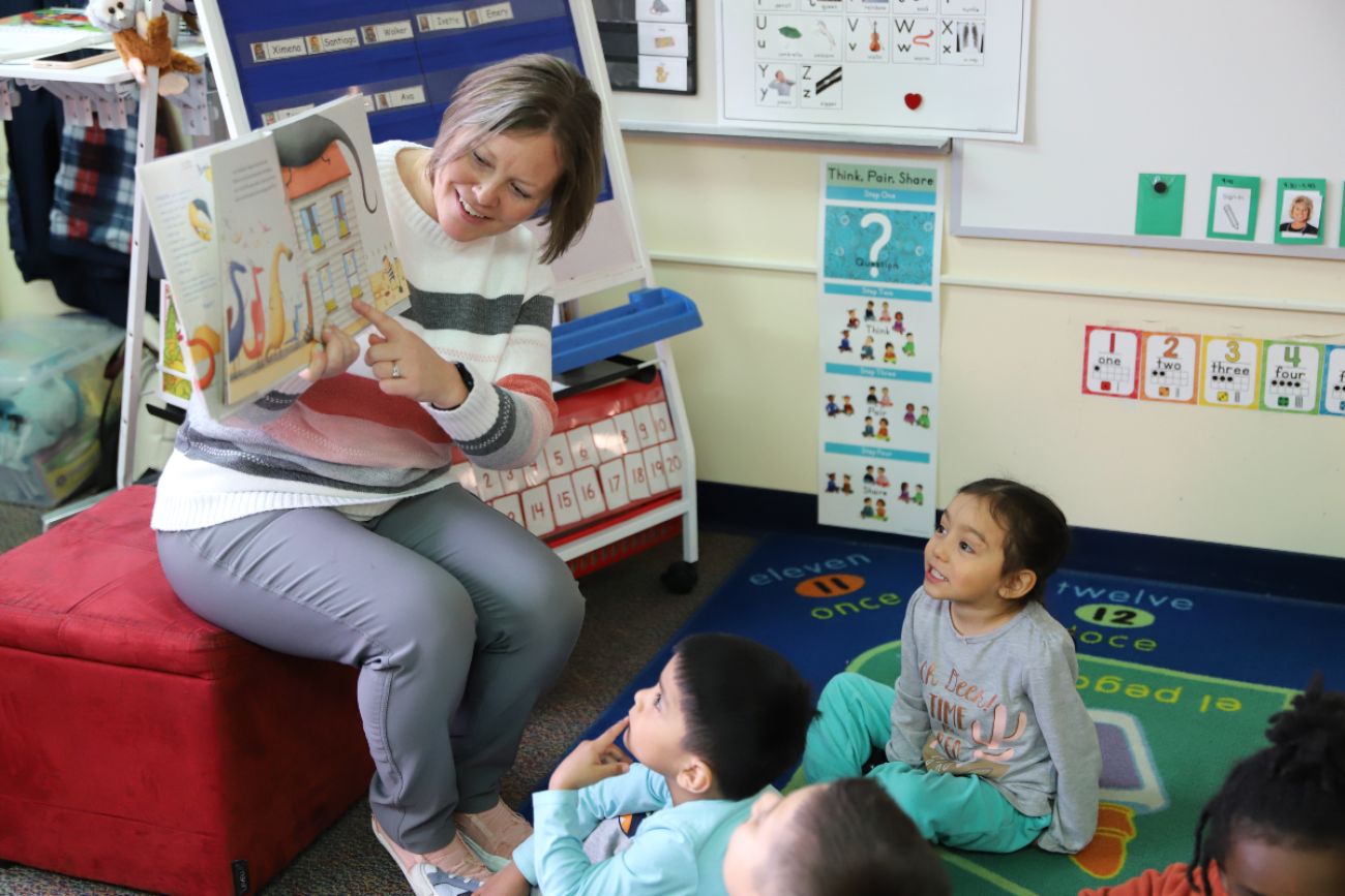 A teacher reading a book to young children in a classroom