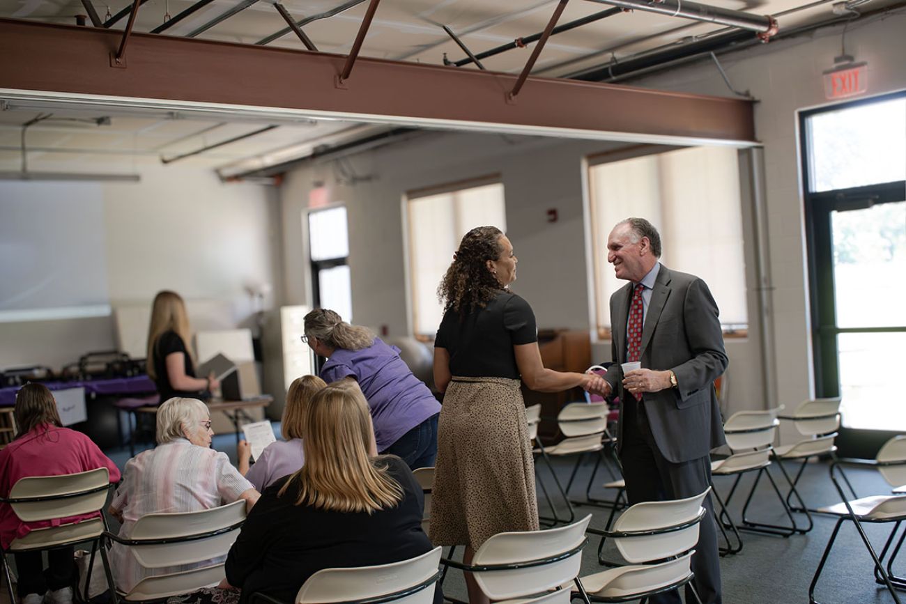 Dr. Peter Lichtenberg shaking the hand and talking to a woman at the event