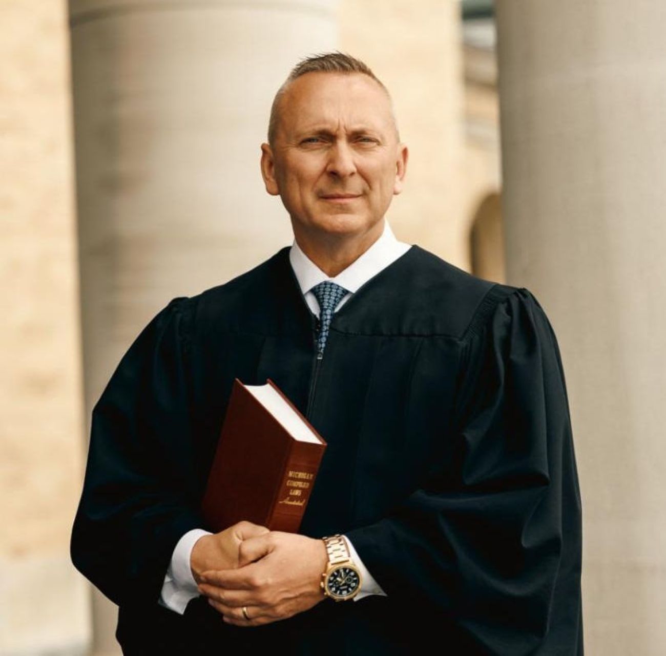 Patrick William O’Grady is wearing black robes and holding a law book