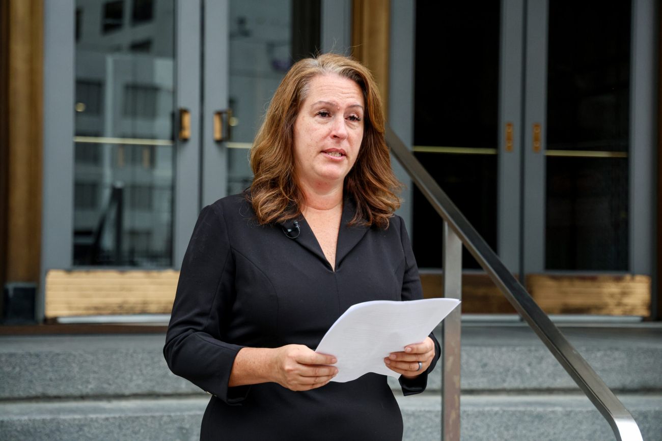 Tina Barton, wearing black, holds a piece of paper