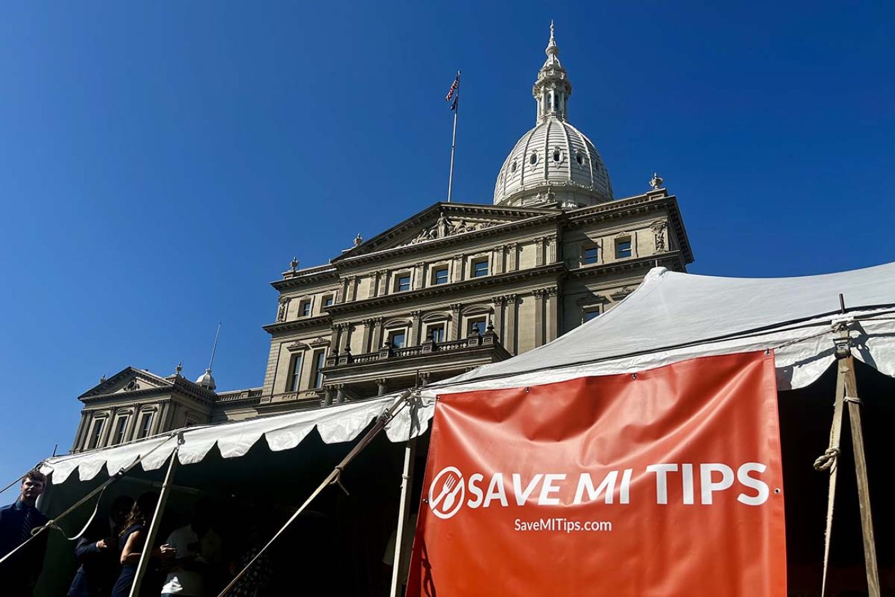 A big red sign in front of the Michigan Capitol