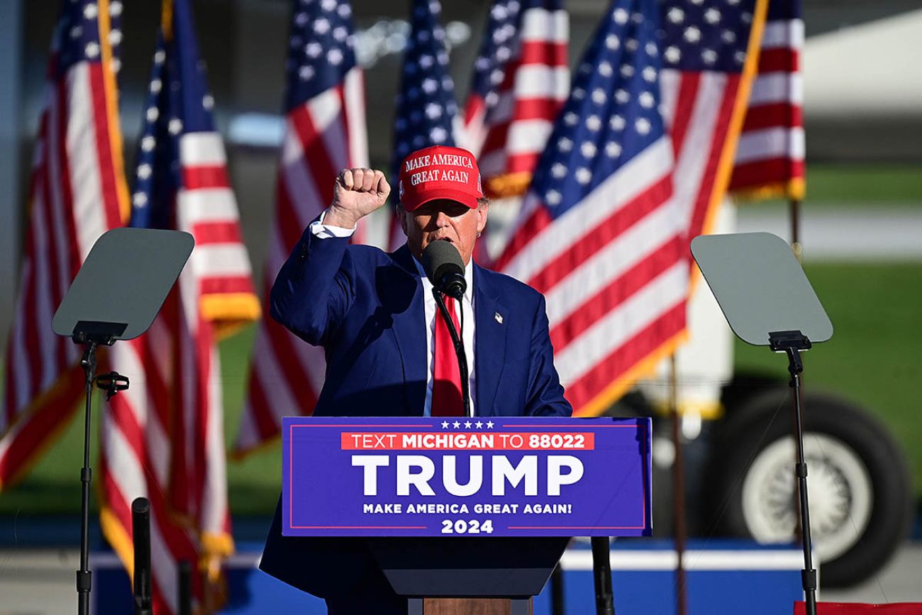 Donald Trump on a stage with American flags at a rally