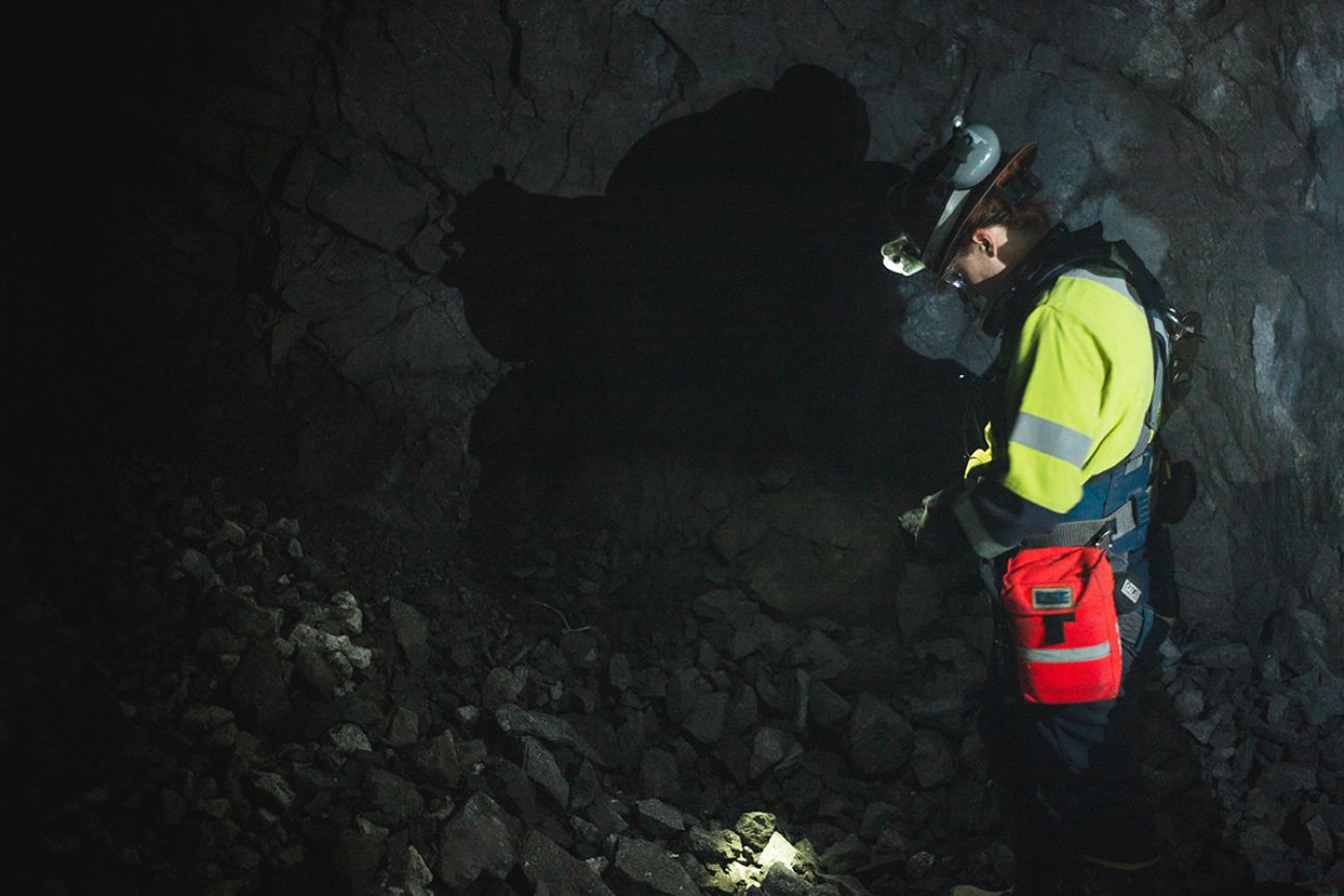 Katy Dorfschmidt, wearing a long sleeve bright green shirt, stands inside a mine