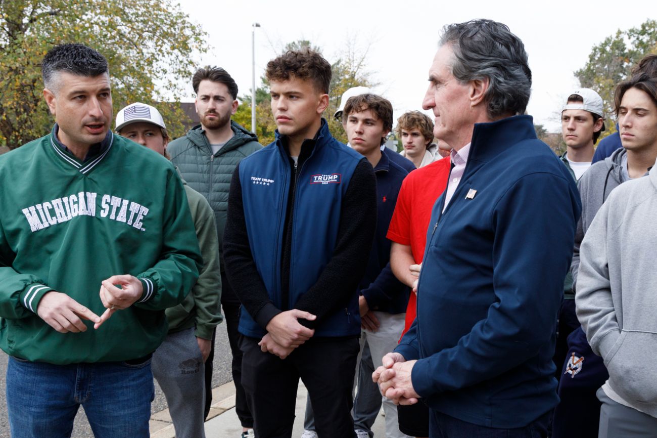 US House candidate Tom Barrett, wearing an MSU jacket, stands next to a young man