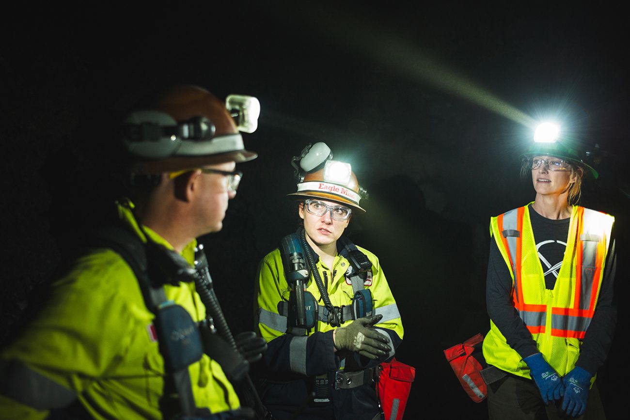 Three miners wearing hard hats with lights on it 