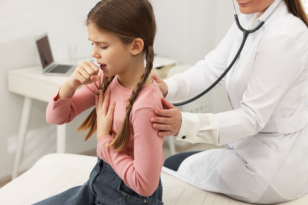 Doctor examining coughing girl in hospital