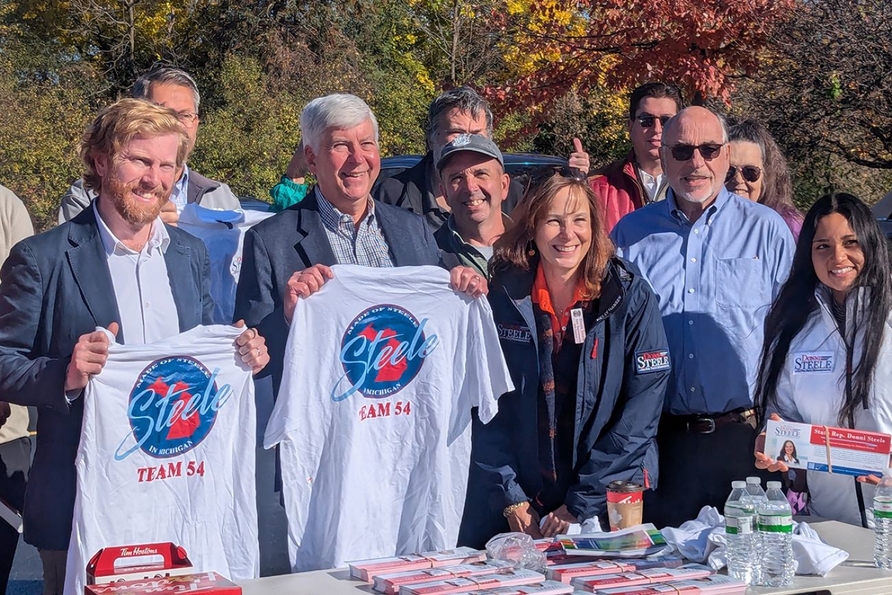 Former Republican Gov. Rick Snyder holds up a t-shirt with Republican Rep. Donni Steele and others