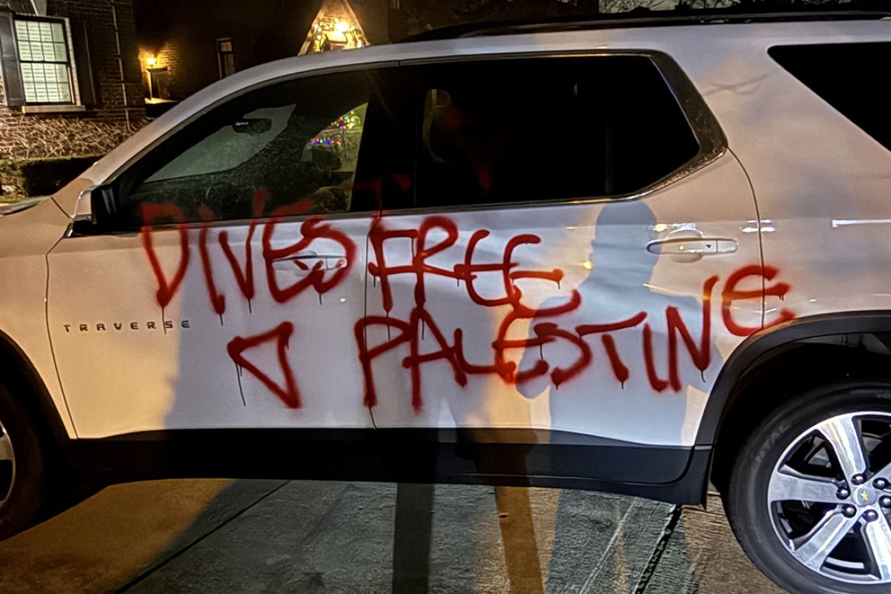 A white car spray painted in red with an inverted triangle. 