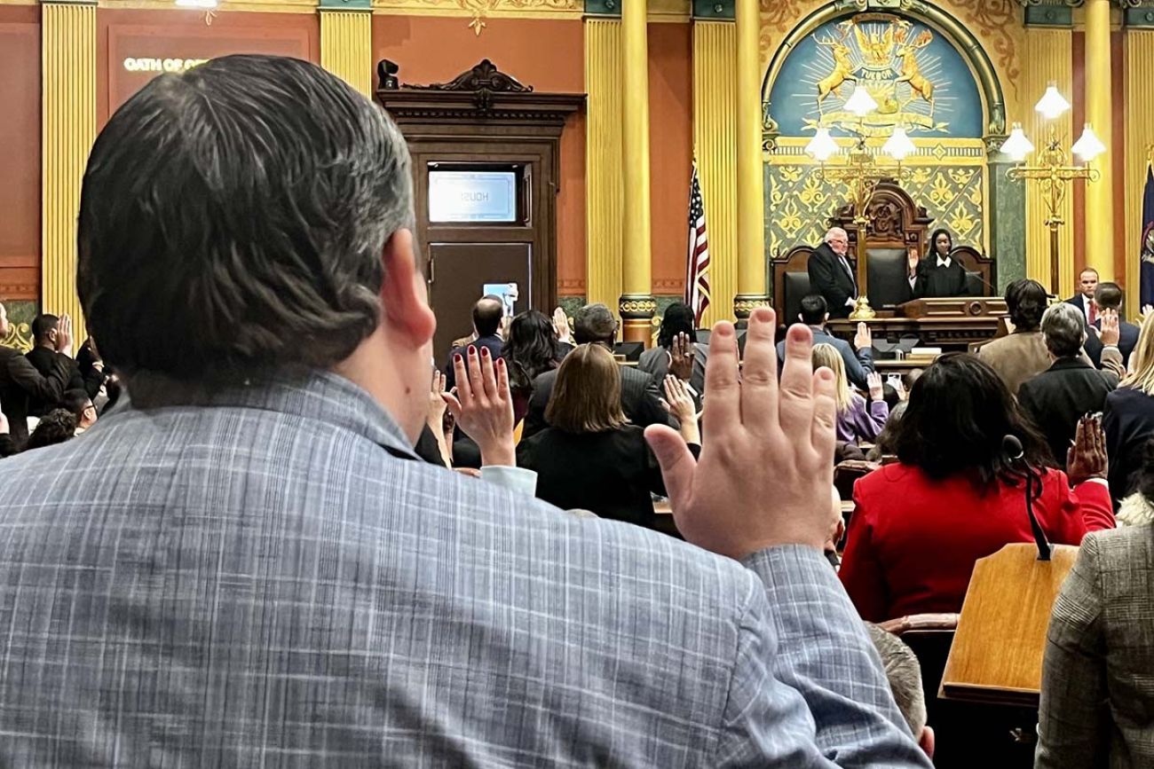 Michigan lawmakers hold their hand up during swearing ceremony