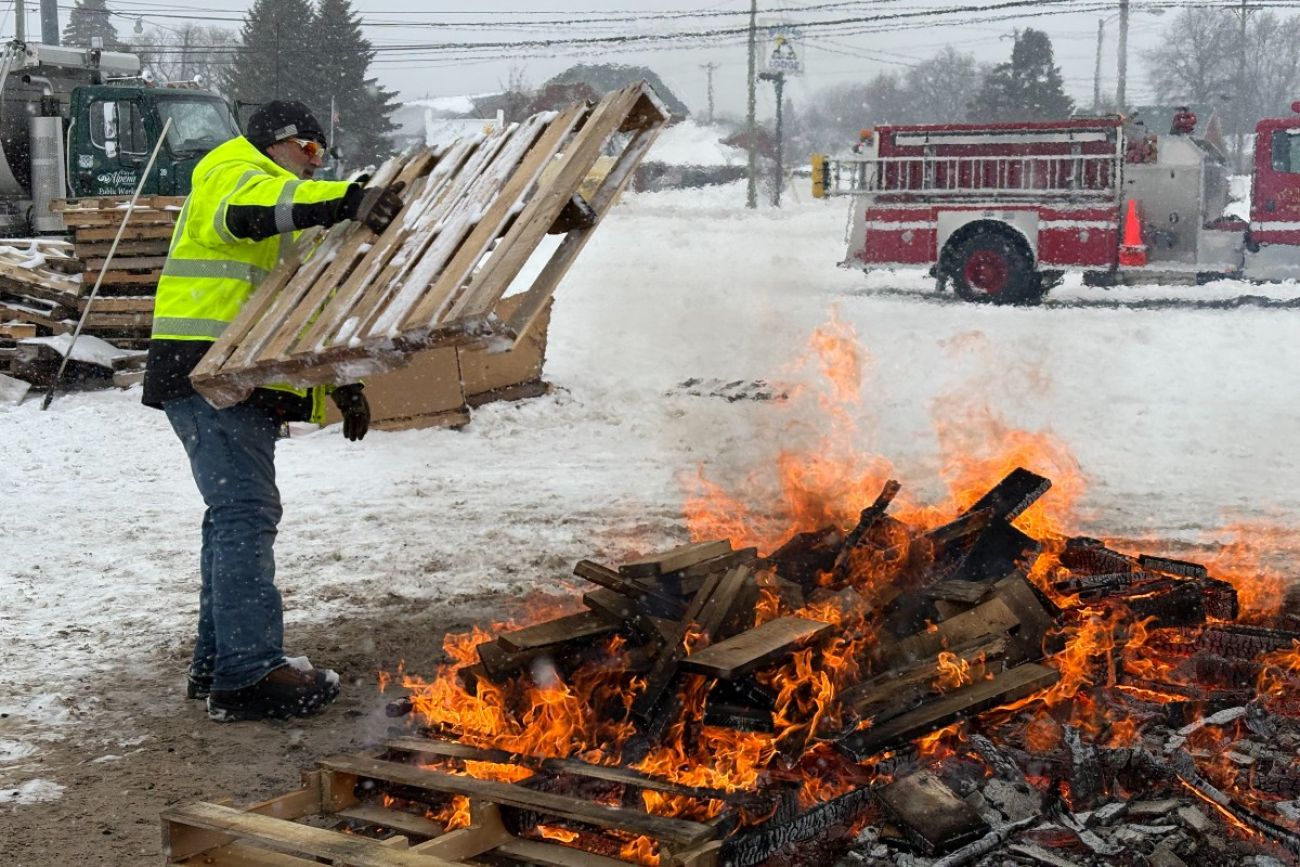 A man adding wood to a fire in Alpena, Michigan. 