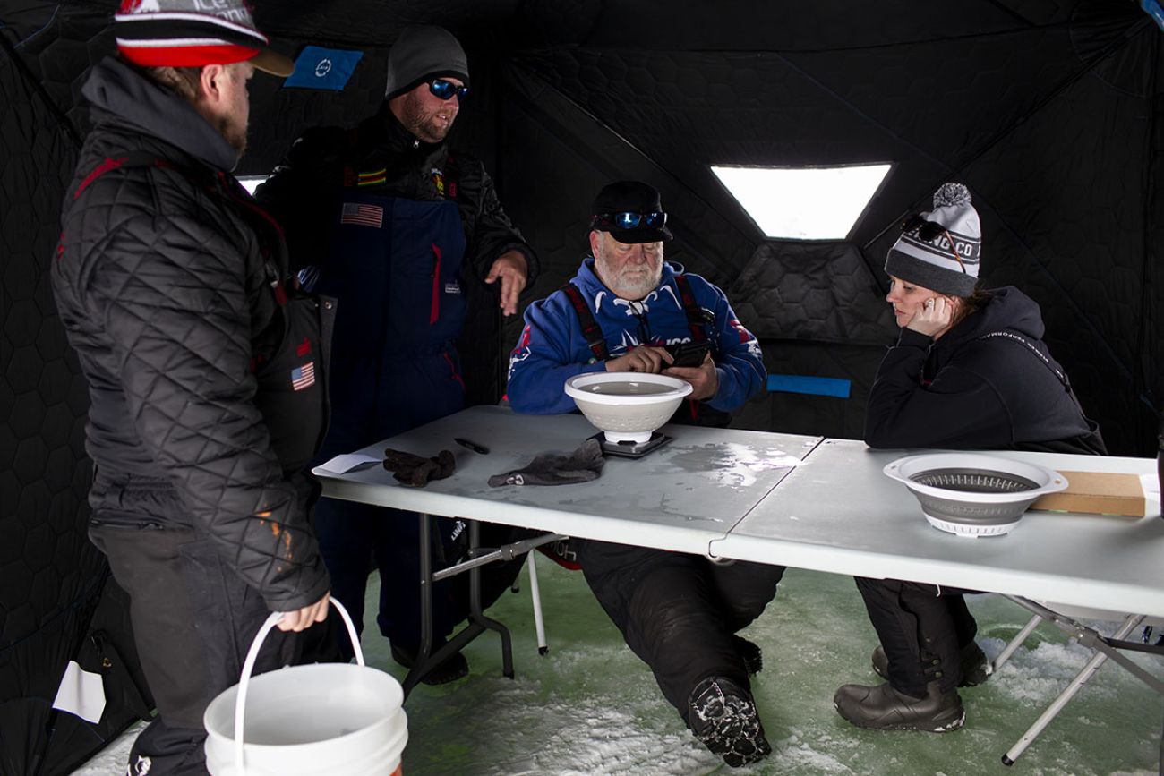 Anglers sitting and standing around the table. 