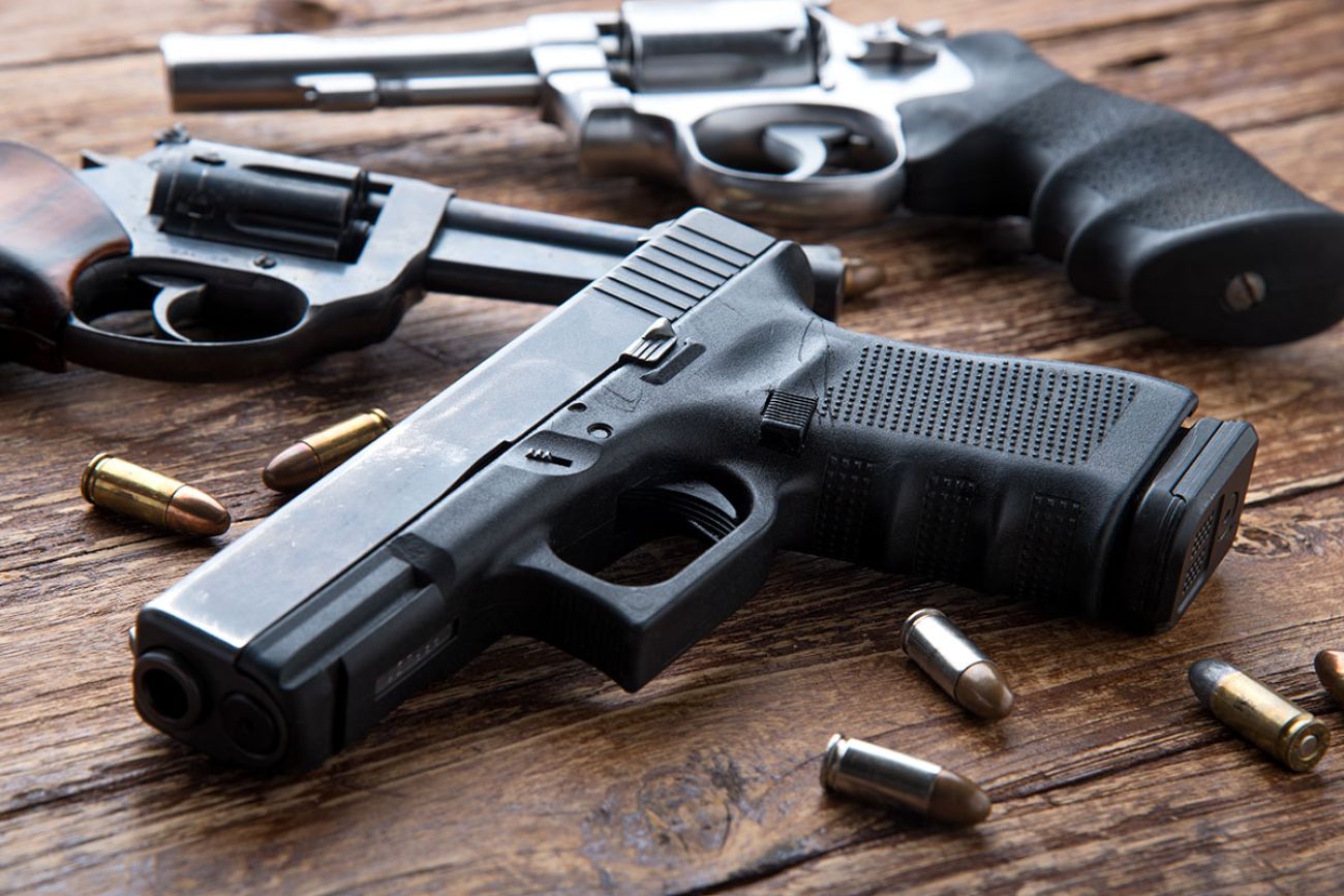 Gun with ammunition on wooden background.