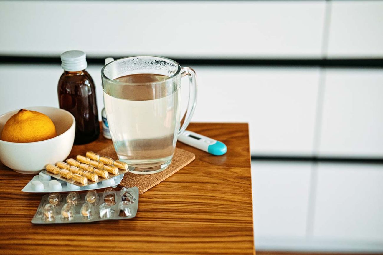 Natural and medical cold and flu remedies on table at home.