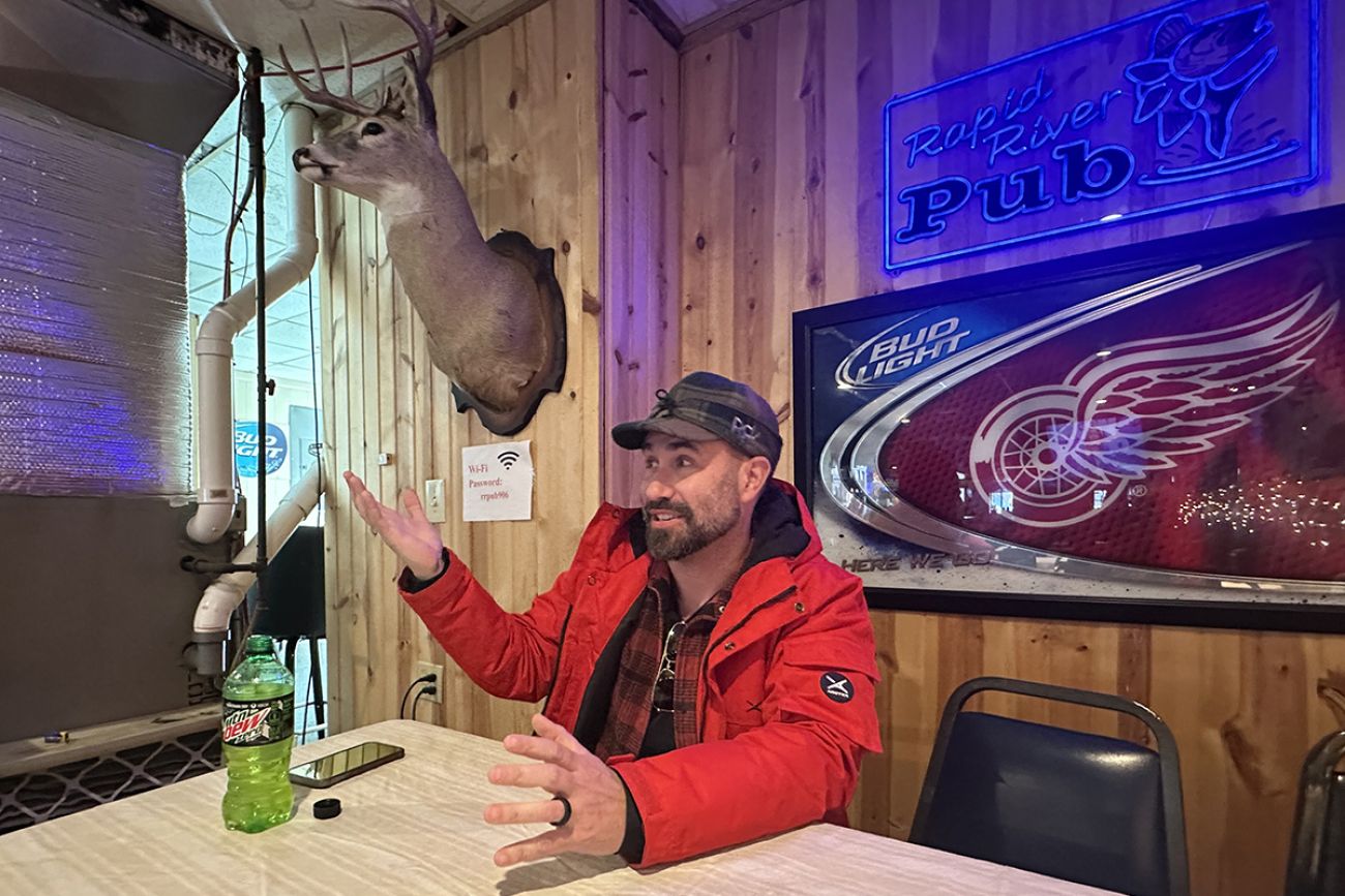 Thomas Szocinski sitting inside the pub. A deer head is on the wall.