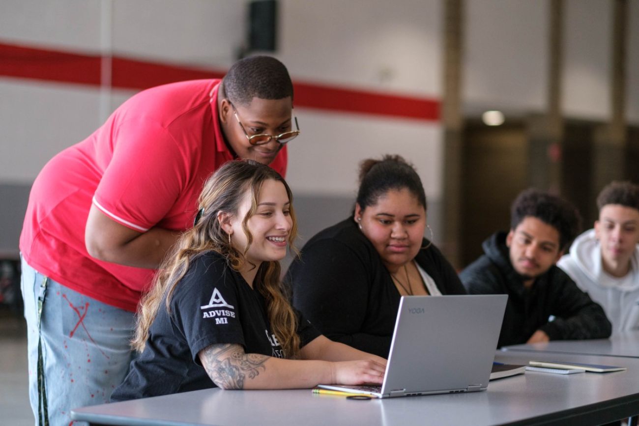 A college advisor helps students with schoolwork
