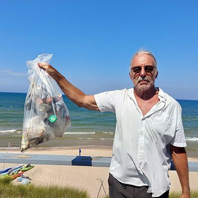 Fisherman is putting fish into the plastic net bag on a beach