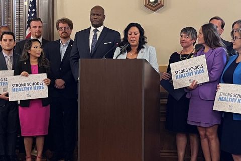 Michigan House Democrats on a press conference. Some are holding signs that says "Strong Schools. Healthy Kids"