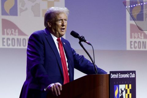 Donald Trump speaking into a microphone at the Detroit Economic Club