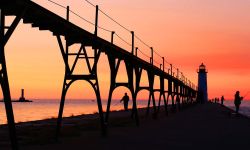 North Pier Lighthouse in Manistee Michigan on lake Michigan at sunset with fishermans silhouettes, in the late summer.